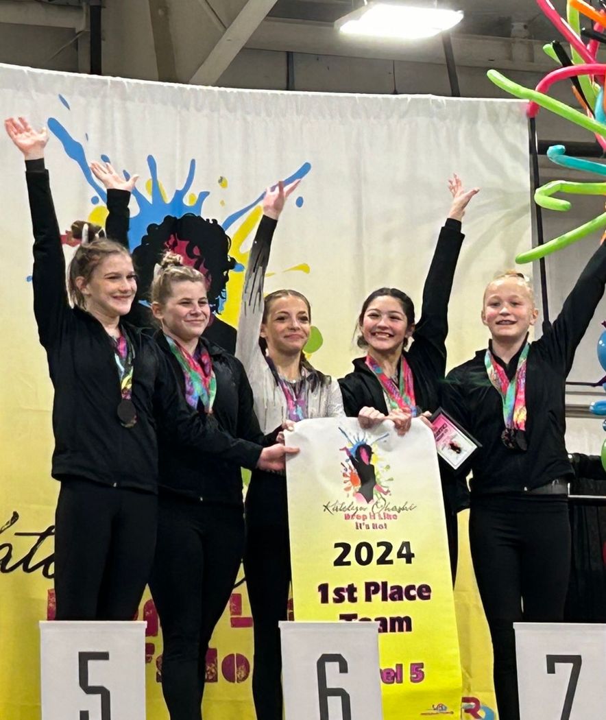 A group of girls are standing on a podium holding a sign that says 2024 1st place team