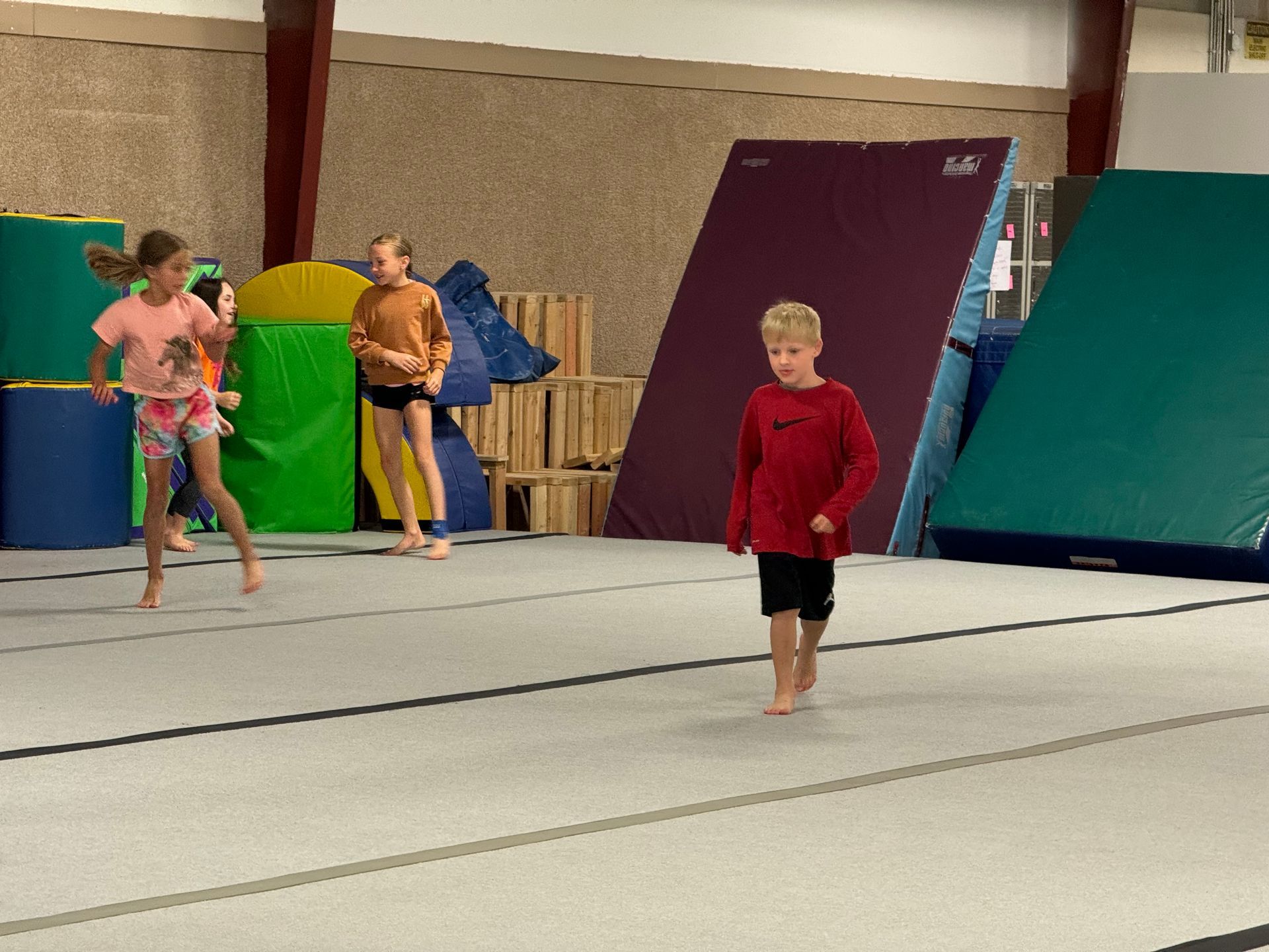 A group of children are practicing gymnastics in a gym.