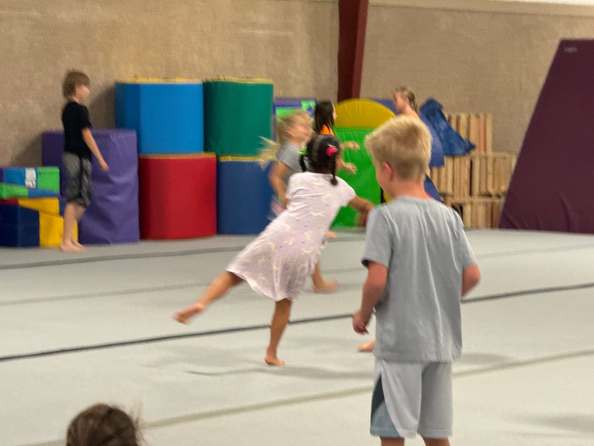 A group of children are playing on a gym floor.