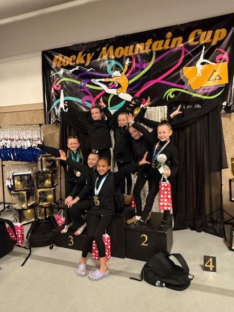 A group of young girls are wearing medals and raising their arms in the air