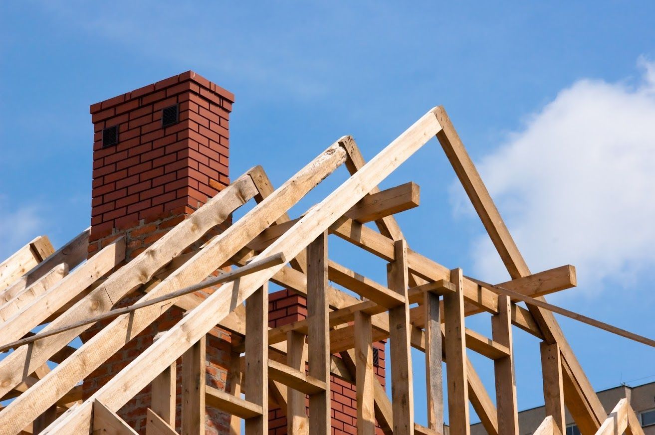 A house is being built with wooden beams and a brick chimney.