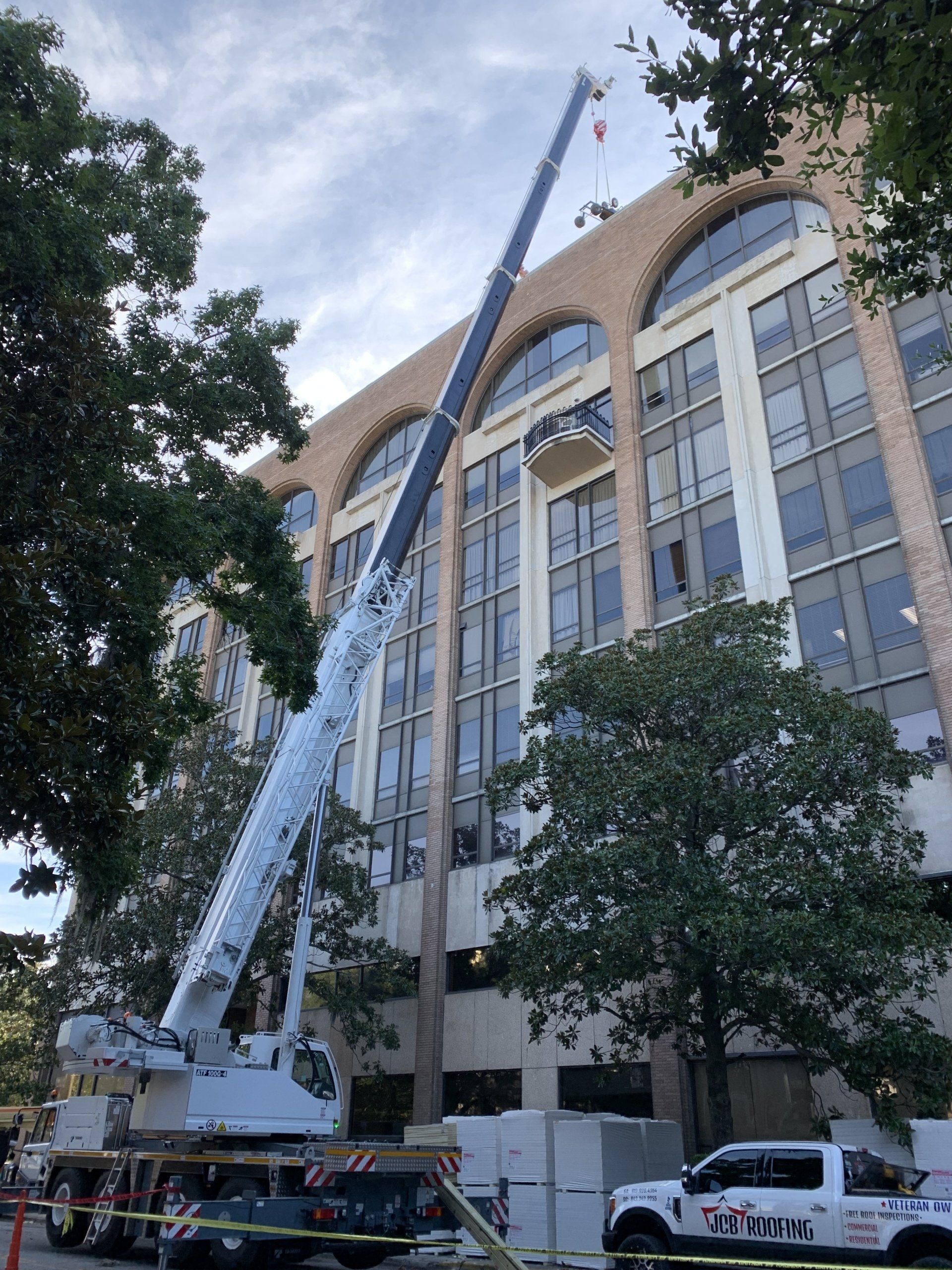 A large crane is being used to remove a window from a building.