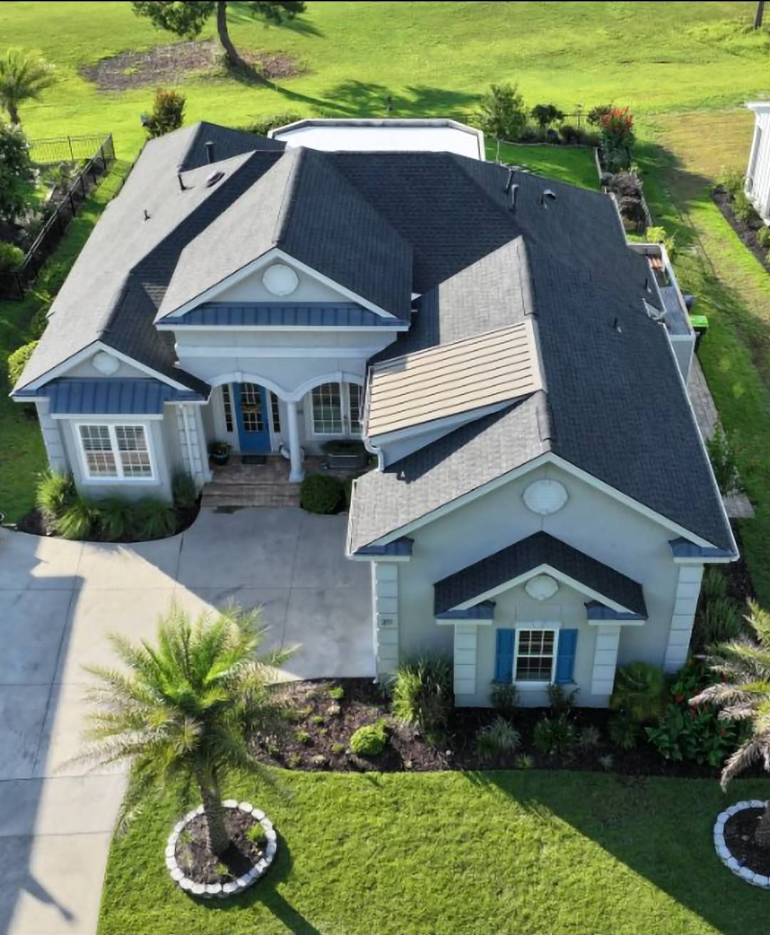Roofer installing dark gray tiles on a sloped roof.