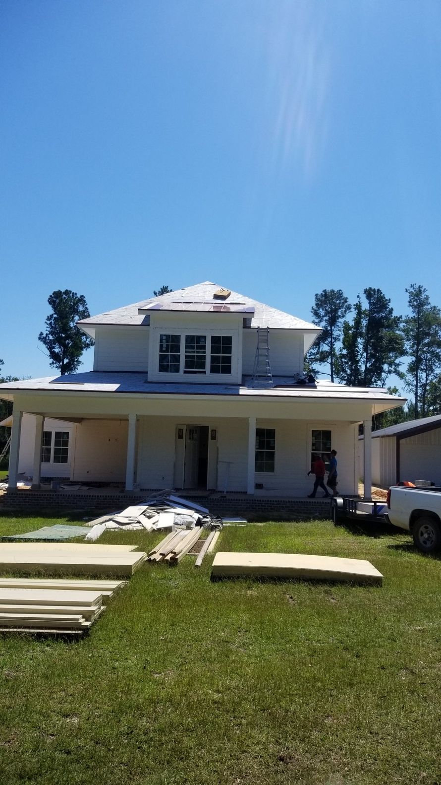 A large white house is being built in the middle of a grassy field.