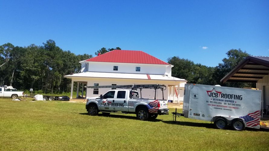 Two roofing trucks are parked in front of a house