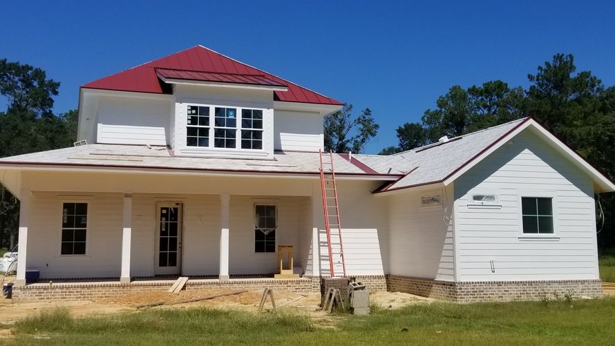 A white house with a red roof is being painted