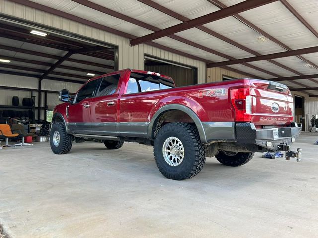 Red lifted pickup truck parked inside a metal garage workshop