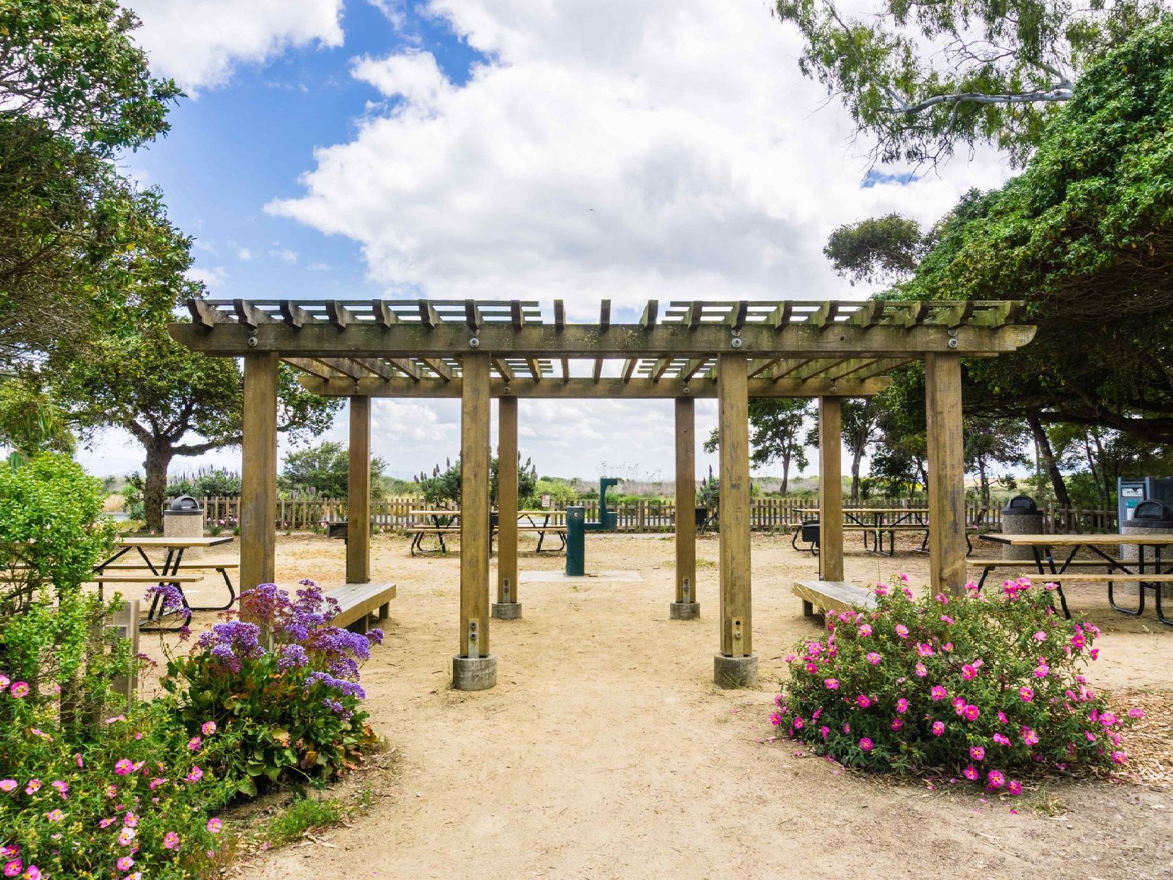 Picnic area with tables and pergola surrounded by flowers