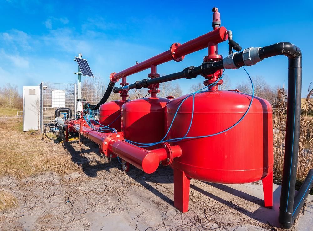 A Row Of Red Tanks Sitting On Top Of A Dirt Field — Mission Solar And Electrical In Tully, QLD