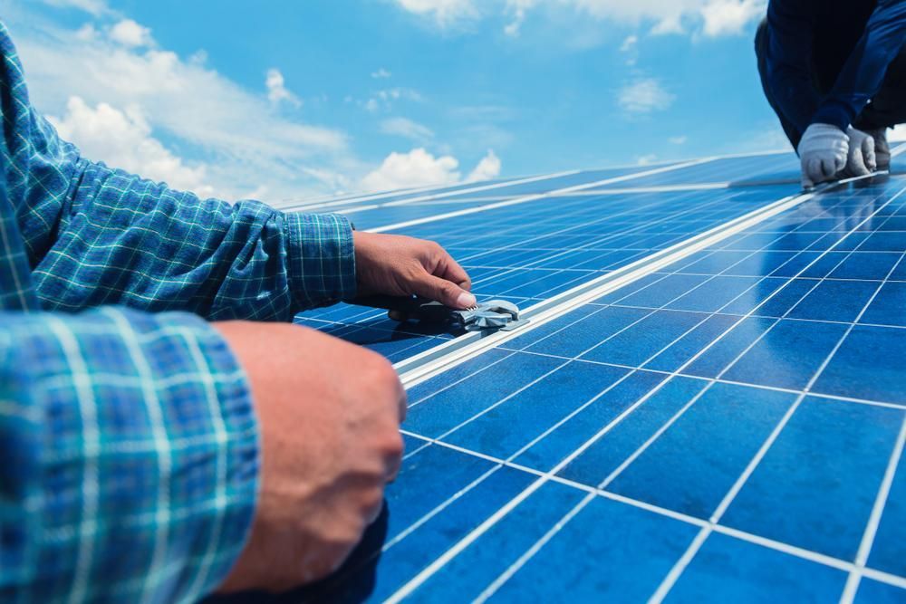 A Man Is Working On A Solar Panel On A Roof — Mission Solar And Electrical In Mission Beach, QLD