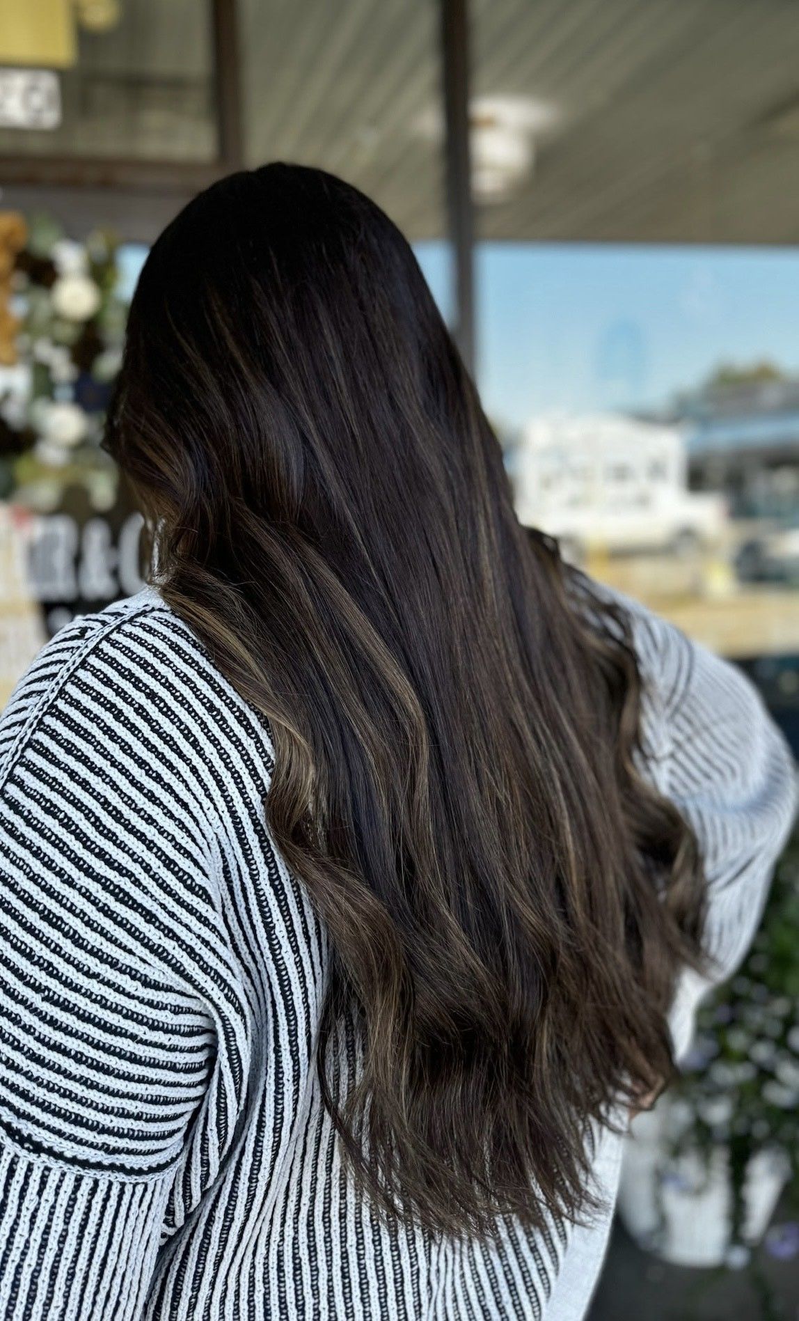 Woman's hair being compared to a hair color swatch, the roots are darker than the tips.