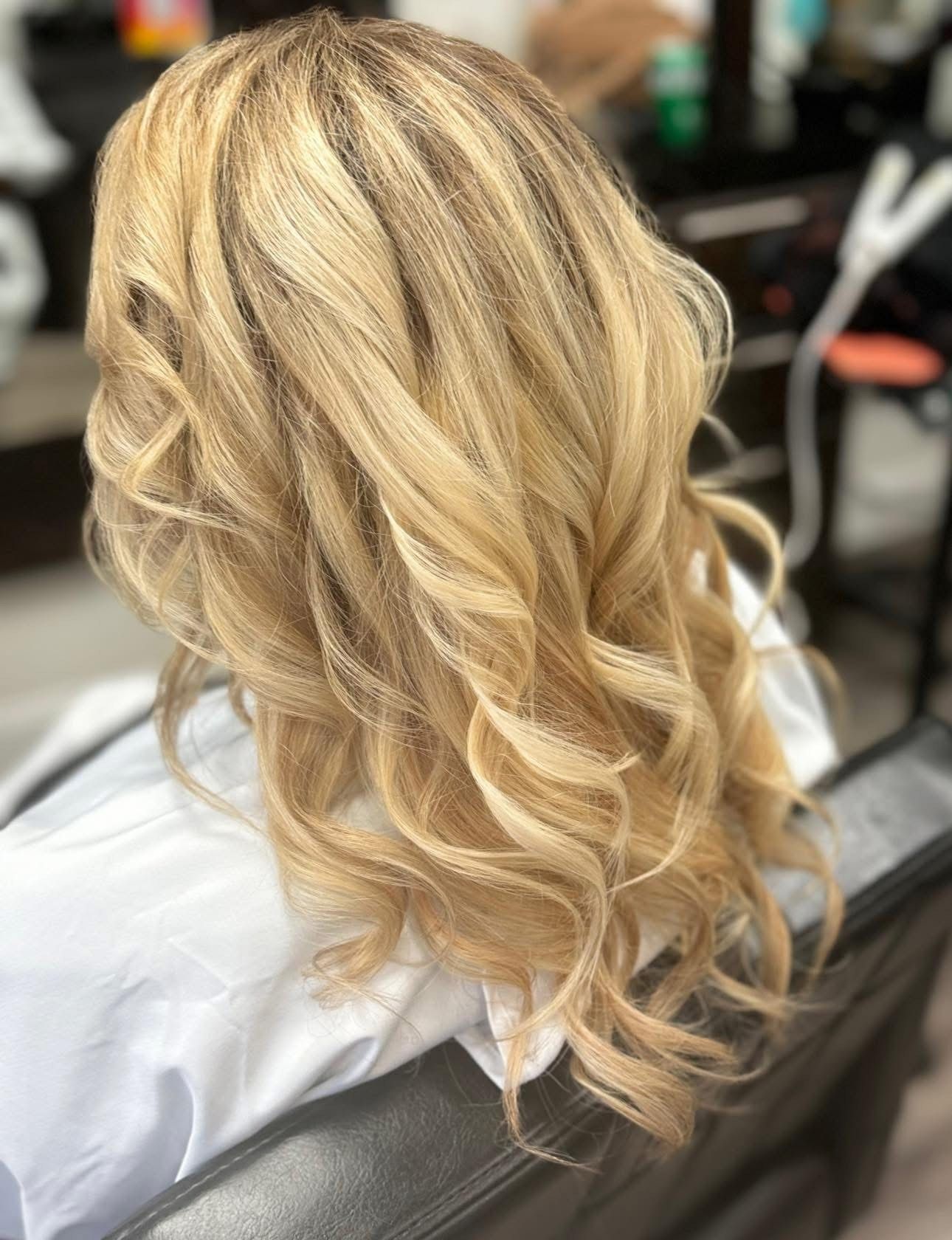 Hair stylist cutting blonde hair with scissors and comb.