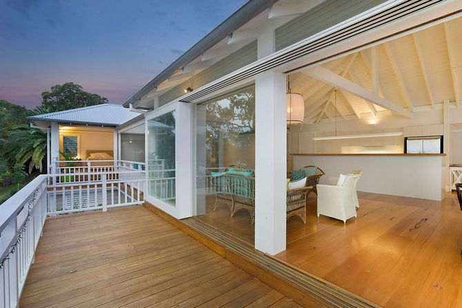 Wooden deck overlooking a bright modern living room at dusk
