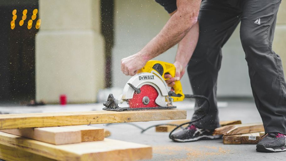 Person cutting wood with a circular saw on a construction site, sawdust flying around the workbench.
