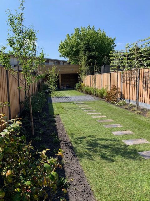 Een achtertuin met een houten hek en een weelderig groen gazon.