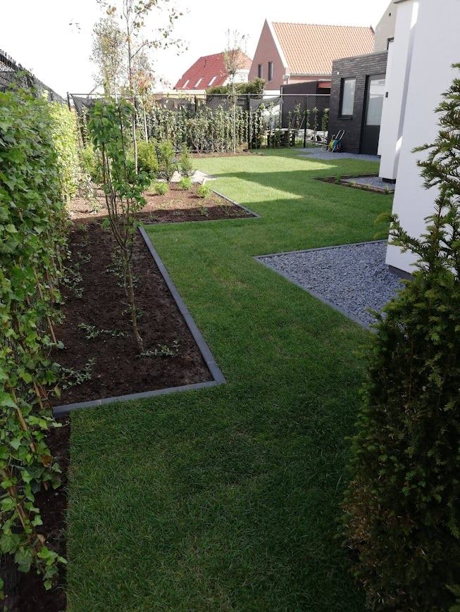 Een tuin met veel gras en bomen voor een huis.