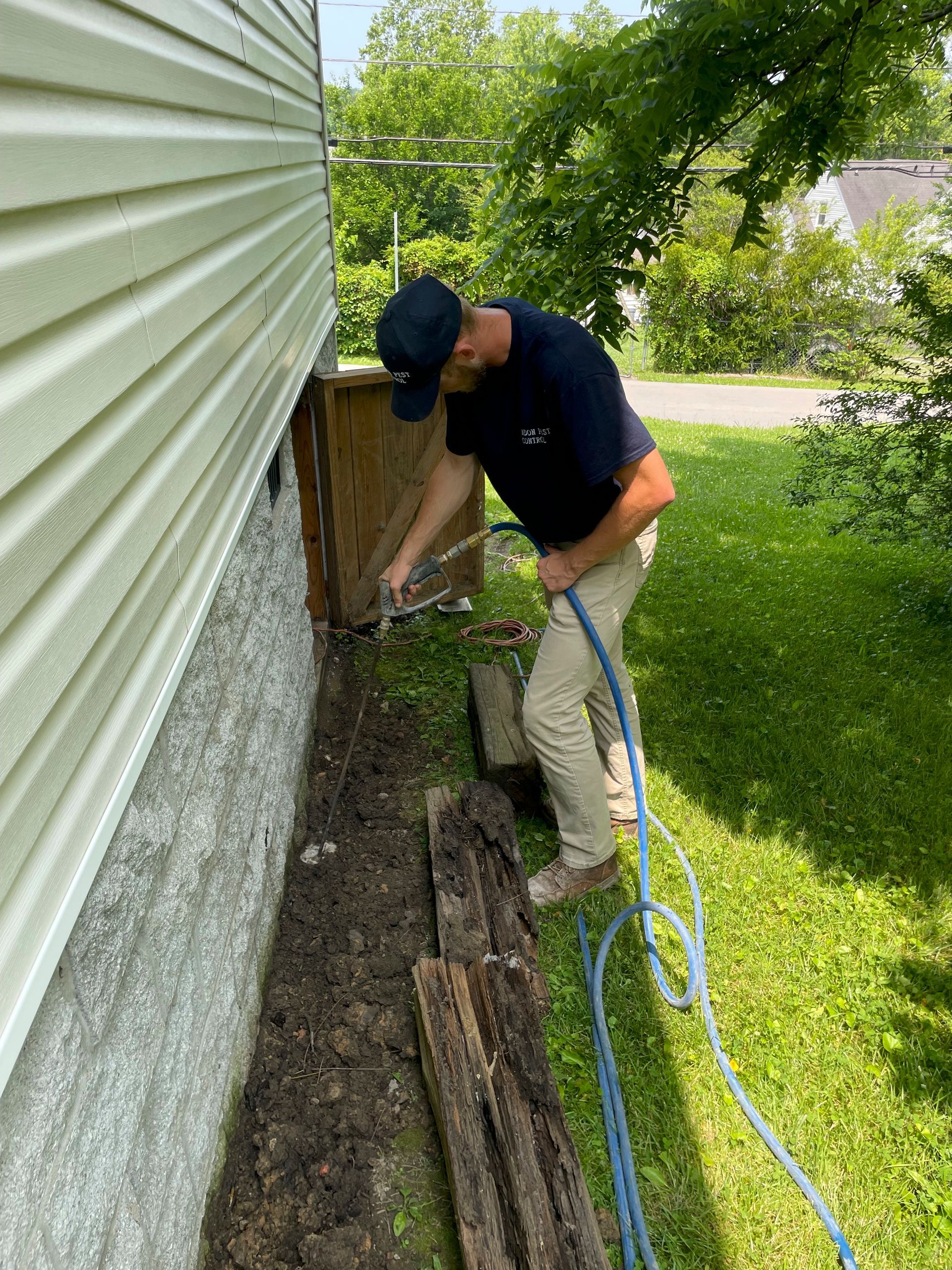 A man is working on the side of a house with a hose.