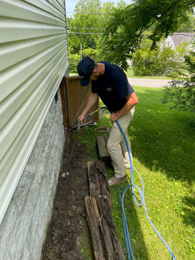 A man is working on the side of a house with a hose.