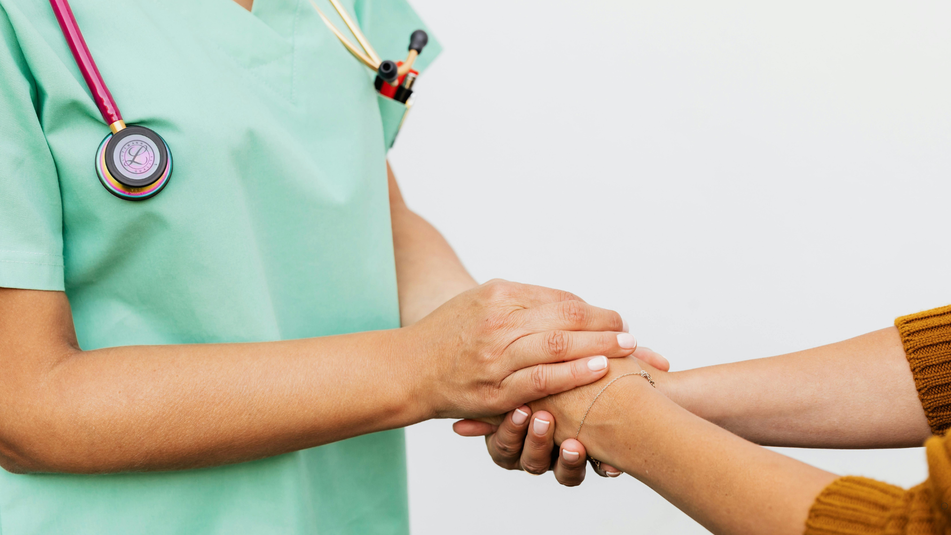 Healthcare professional gently holding a patient's hand, offering support and comfort during a medical consultation.