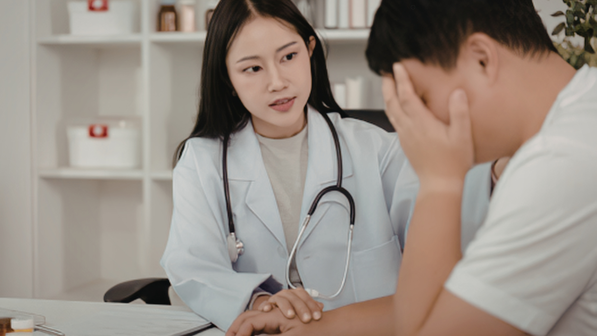 Doctor comforting a patient who is holding their head in distress, offering compassionate care in a medical office.
