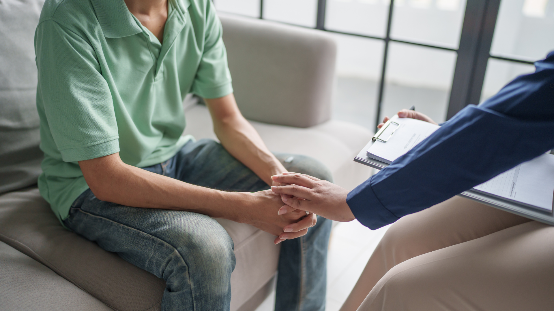 Therapist offering supportive hand to a patient during a counseling session, promoting a sense of trust and care.