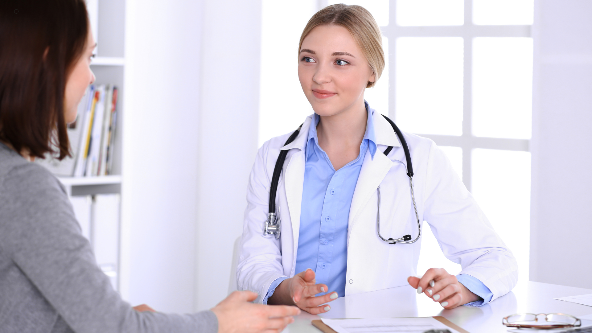 A doctor and patient engaged in a conversation in a well-lit clinic, with the doctor listening attentively while the patient speaks.