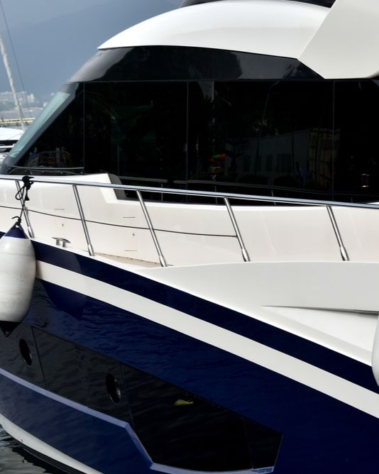 White and blue yacht with dark tinted windows, docked.
