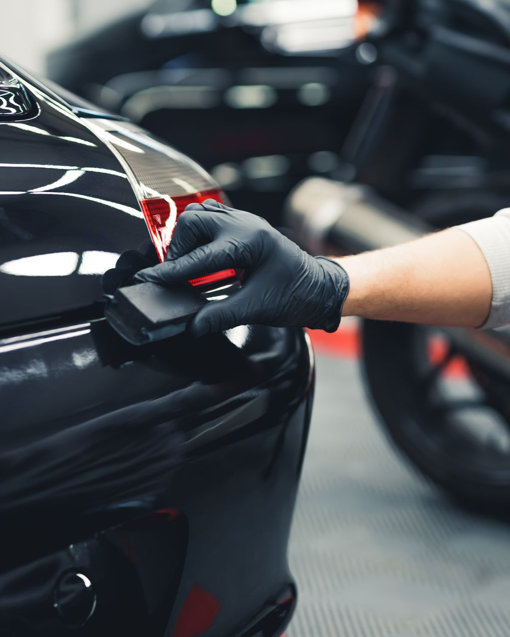 Person applying ceramic coating to a black motorcycle, wearing black gloves.