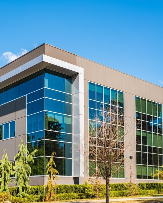 Modern office building with large glass windows and a blue sky background.