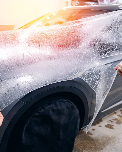 Installer peeling back paint protection film on a wet car fender during application