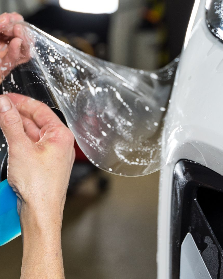 A person is wrapping a car with clear plastic