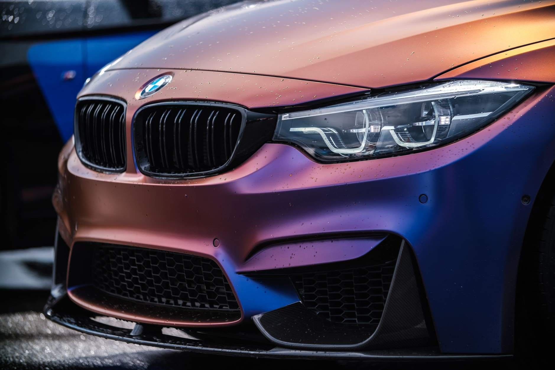 Close-up of a BMW car with a color-shifting paint job, transitioning from blue to purple to copper.