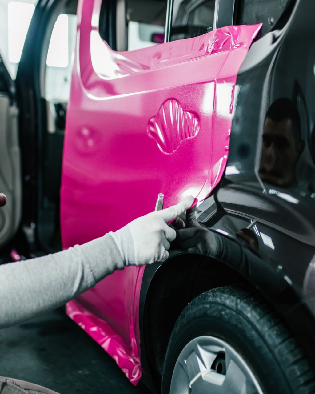 A car is covered in plastic wrap in a garage.