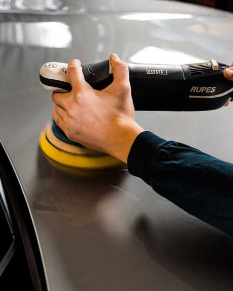 A person is cleaning the interior of a car with a vacuum cleaner.