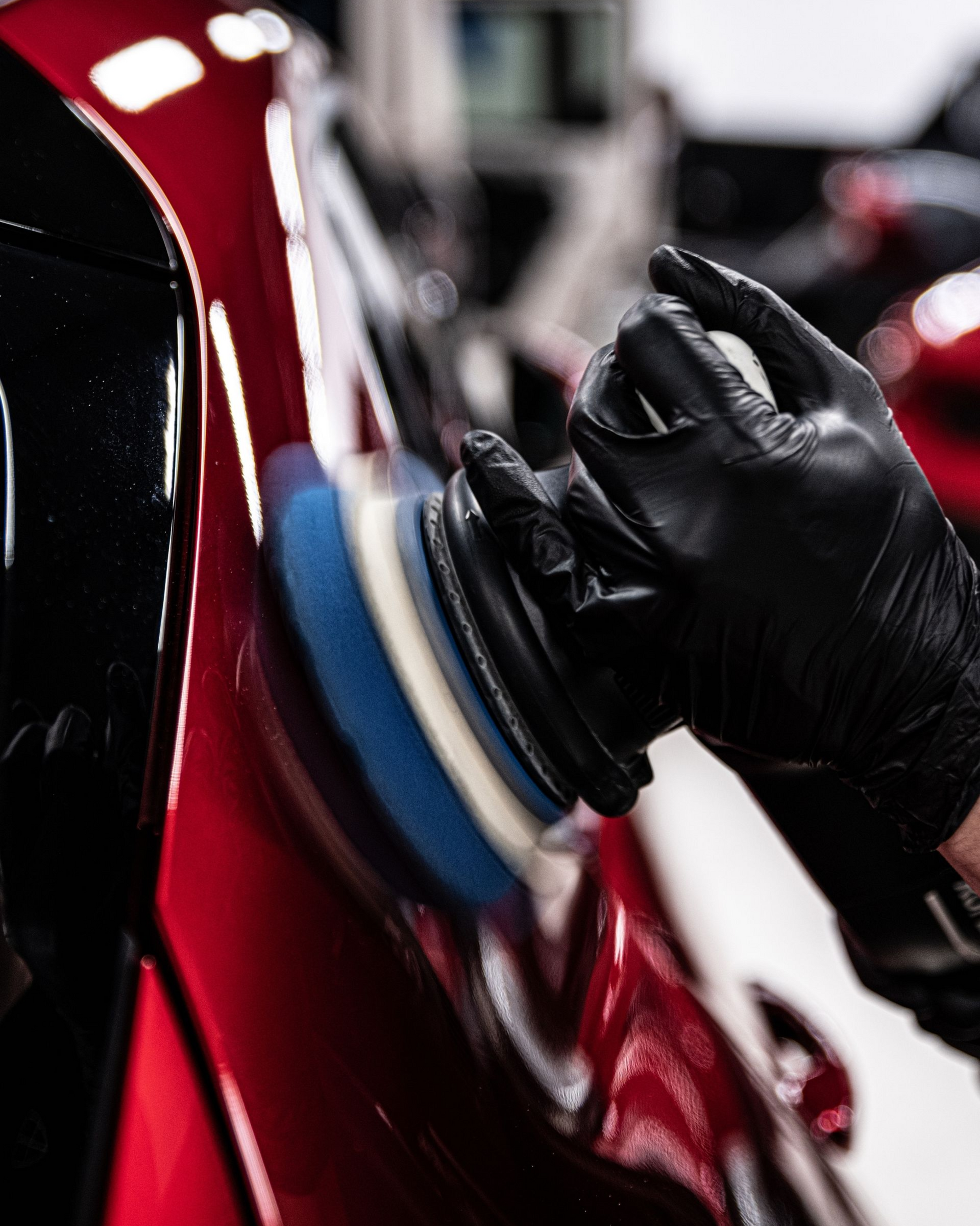 A person is cleaning a car with a pink squeegee.