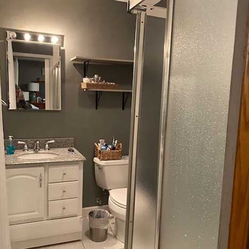 A bathroom with a sink , toilet , mirror and shower stall.