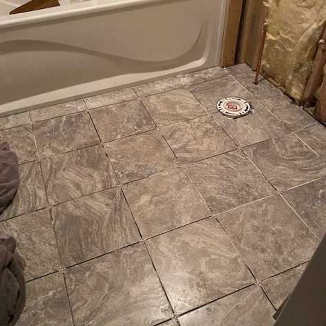 A bathroom with a tiled floor and a bathtub.