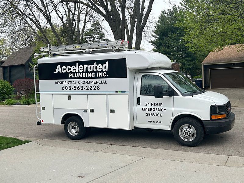 A white van from accelerated plumbing inc. is parked in a driveway.