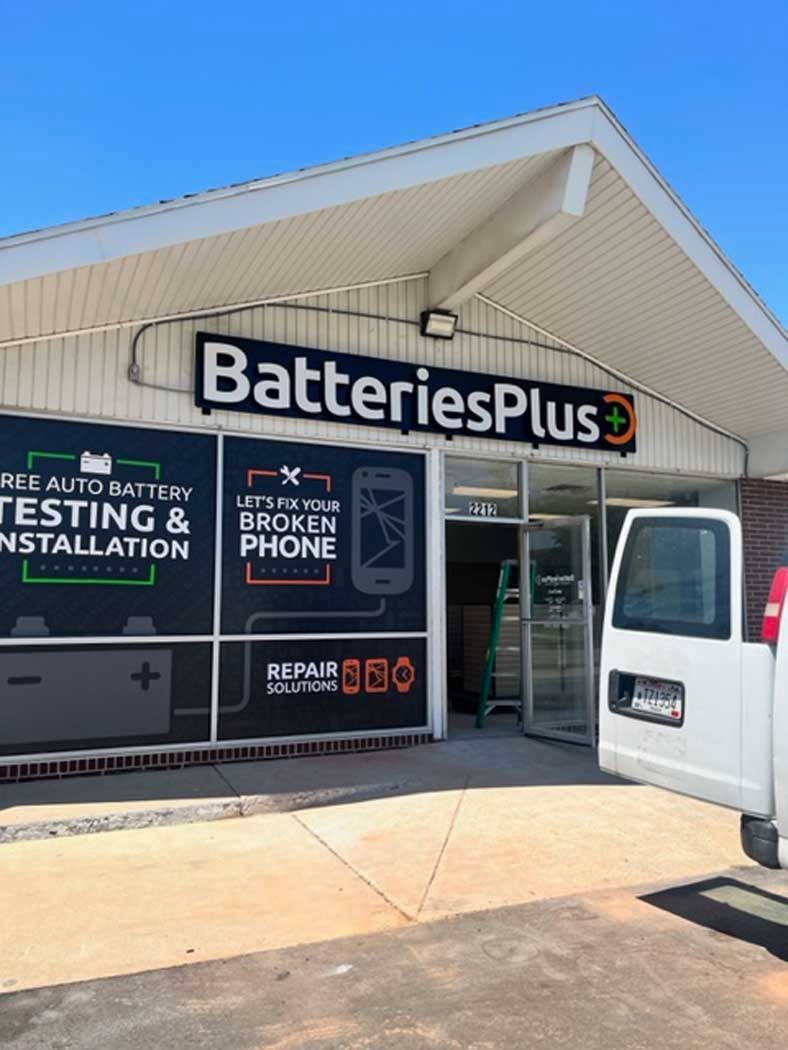 A white van is parked in front of a store called batteries plus