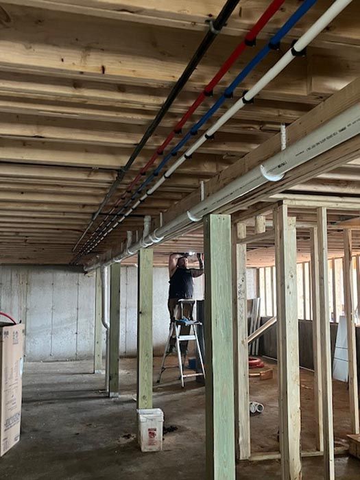 A man is standing on a ladder in a basement under construction.