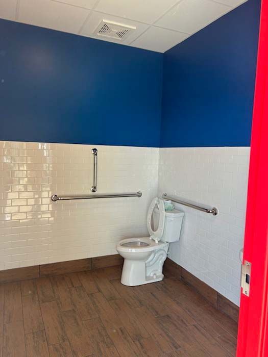 A bathroom with a toilet and a red door.