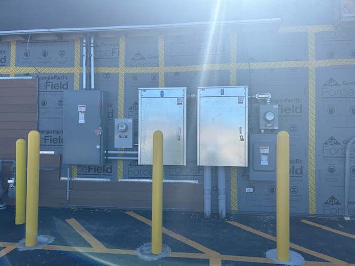 There are a lot of electrical boxes on the side of a building.