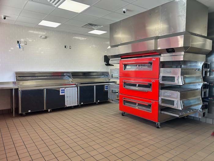 A kitchen with stainless steel appliances and a red oven.