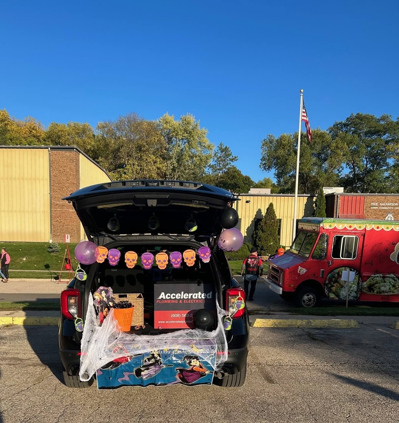 A car with the trunk open is decorated for a trick or treat event.