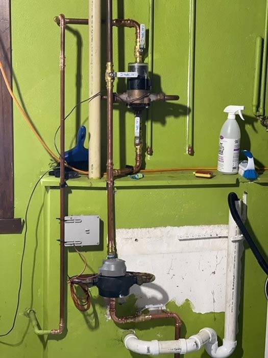 A green wall with pipes and a spray bottle