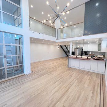 A large empty room with hardwood floors and a kitchen.