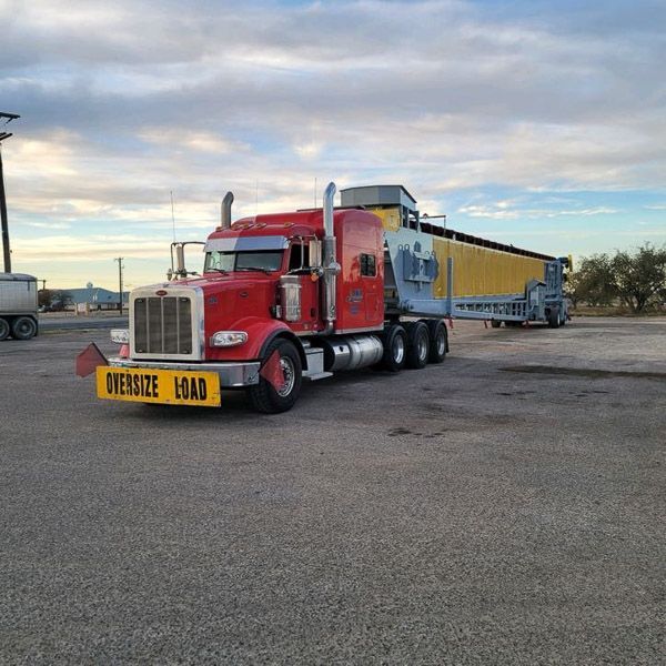 A red semi truck with a yellow sign that says oversize load
