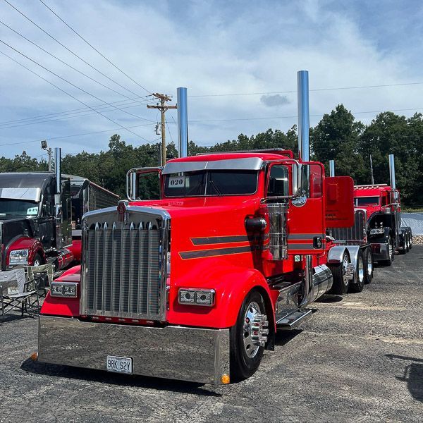 A row of red semi trucks are parked in a parking lot