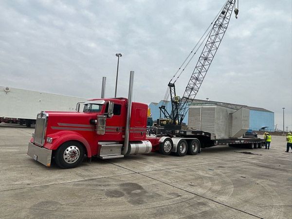 A red semi truck is being towed by a crane.