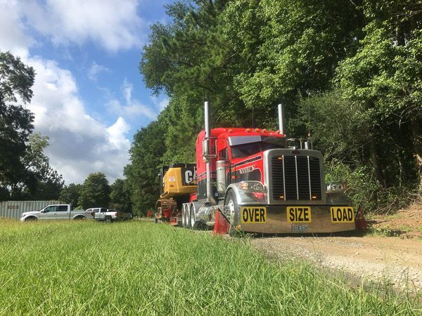 A red semi truck is parked in a grassy field.